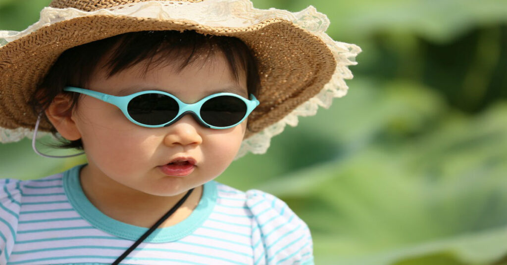 Female toddler in a straw hat and sunglasses