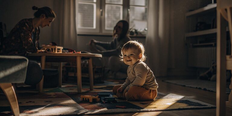 A happy toddler plays safely with toys in a clean, sunlit room offering high quality childcare.