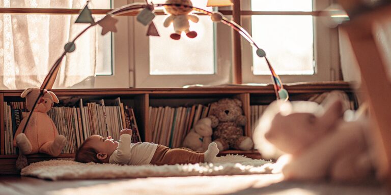 Infant on a play mat enjoying early learning with colorful toys and books.
