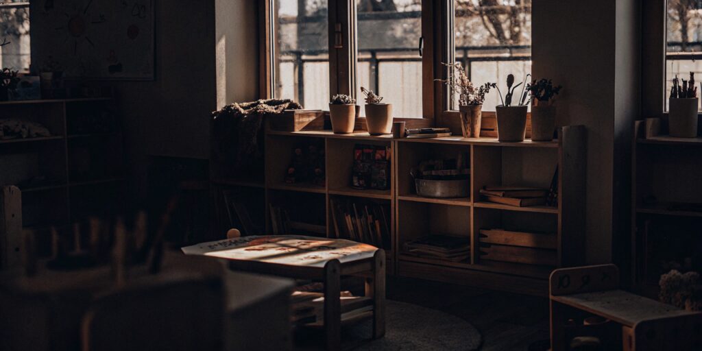 A bright Reggio Emilia inspired preschool classroom with wooden furniture and natural materials.