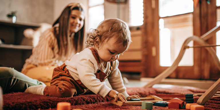 A child explores educational toys in a learning daycare while a teacher observes.