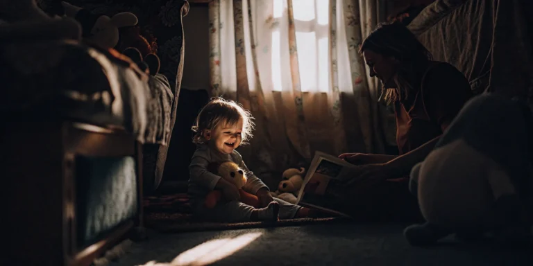 A toddler and adult reading together, a social and emotional development activity for 2-3 year olds.
