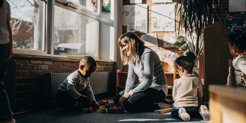 Preschool children and a teacher exploring inquiry based learning with building blocks in a classroom.