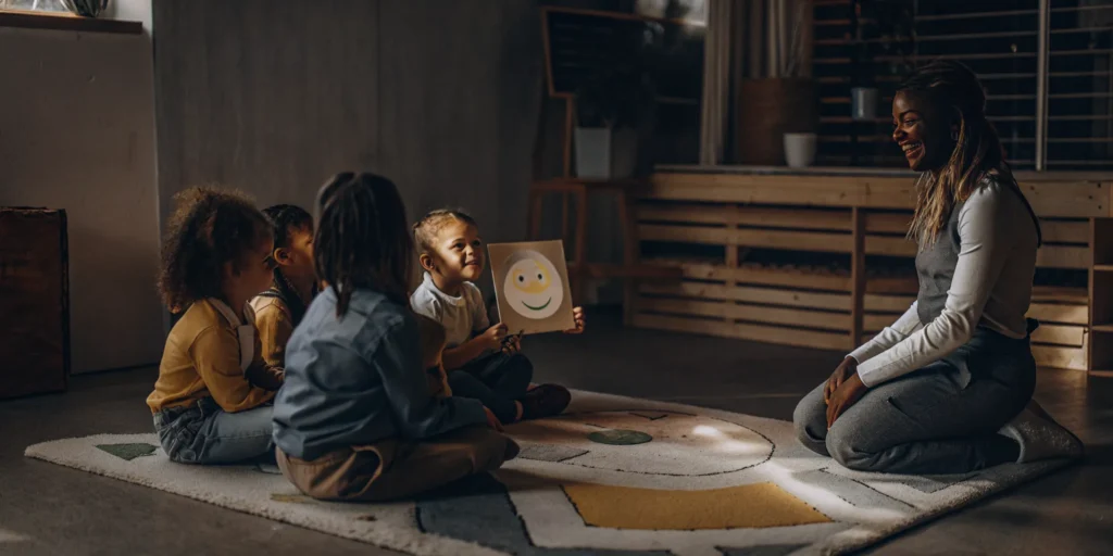 A teacher and children in an emotional development program learn about feelings with a smiley face.