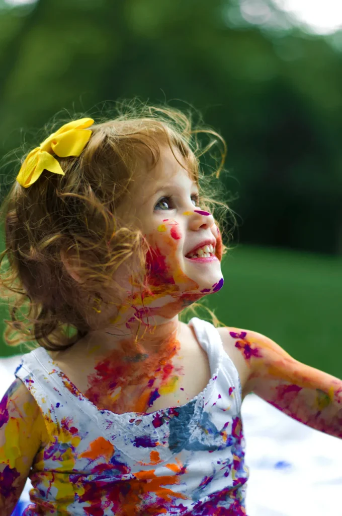 Toddler playing outdoors, practicing gross motor skills by running and jumping