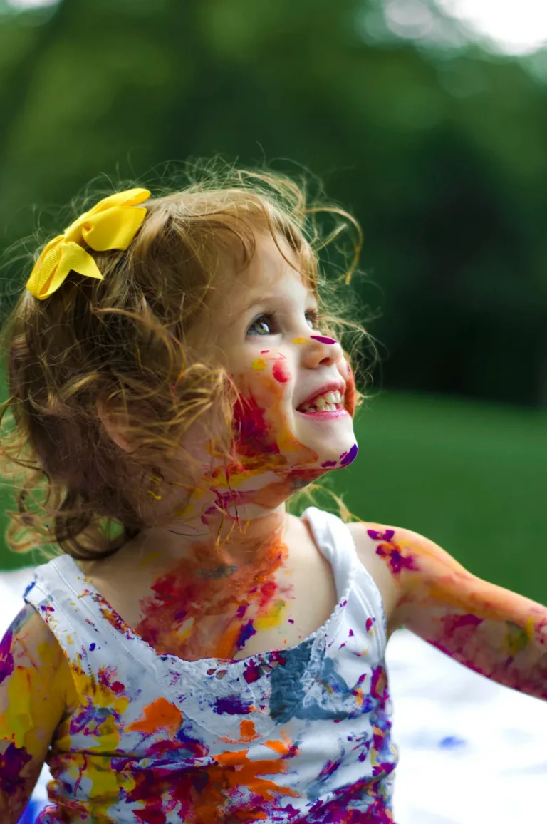 Toddler playing outdoors, practicing gross motor skills by running and jumping