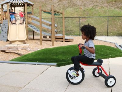 a child on a tricycle at one of our playgrounds